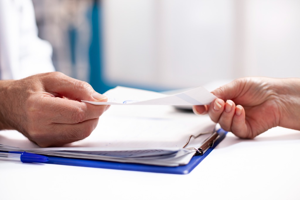 Healthcare professional handing a prescription to a patient in a clinical setting - Prescriber Portal coming soon to Platinum Pharmacy UK